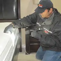 Bed bug inspection technician checking a mattress and bed frame for signs of infestation in Tulsa, OK