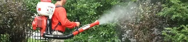 Mosquito control technician fogging shrubs and landscaping for mosquito treatment in Tulsa, OK