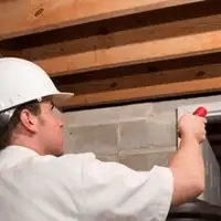 Termite inspection technician checking a basement wall and framing for termite activity in Tulsa, OK